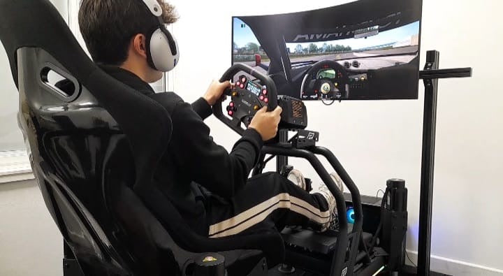 Person using a racing simulator with a steering wheel and headset.